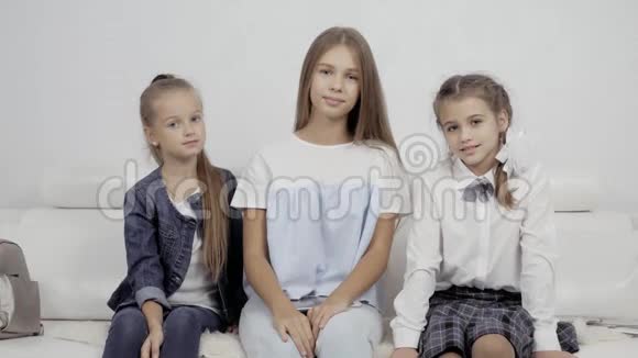 两个幸福的小妹妹在舒适的客厅和三个女孩的舒适沙发上温柔地拥抱着视频的预览图