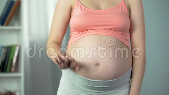 女士显示良好的手势温柔地触摸她怀孕的腹部医疗保健视频的预览图