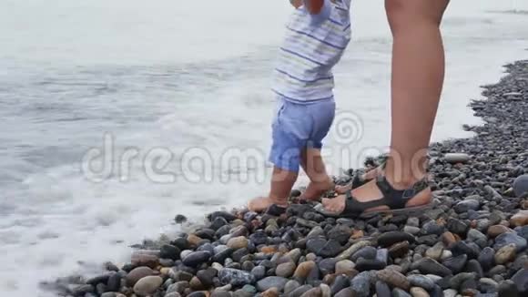 一个小男孩正在海滩上和他的母亲玩耍和散步视频的预览图