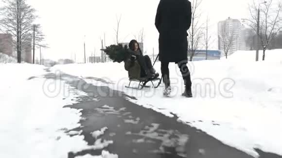 男人在雪地上拉着女孩冬季乐趣视频的预览图