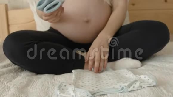 孕妇为未来的孩子看小衣服视频的预览图