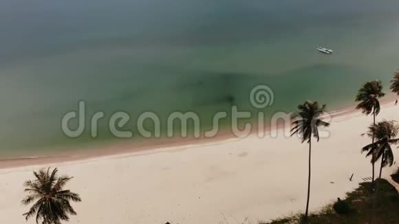空中无人驾驶飞机观看绿色海洋与小船和白色沙滩海岸与热带植物在泰国椰子棕榈视频的预览图
