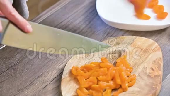 用刀在切割板上切割杏干的雌手烹饪素食视频的预览图