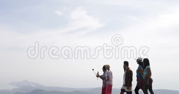 一群快乐的游客走在山顶上手持行动摄像机快乐的男人和女人制作美丽的视频视频的预览图