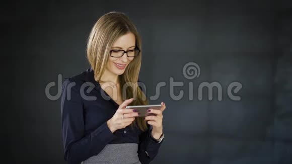商务女性站在办公室的近旁背景是深灰色的墙用智能手机打字信息视频的预览图