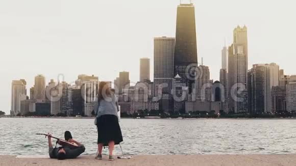 美国芝加哥密歇根湖畔的年轻创意夫妇女人画画妈妈弹吉他躺在岸上视频的预览图