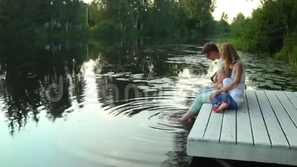 一家人坐在绿意环抱的湖边视频的预览图
