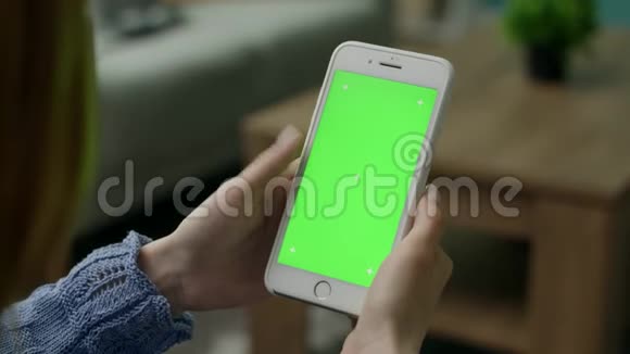 女人在家用绿色锁屏智能手机在沙发上唱歌视频的预览图