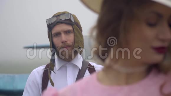 把一个戴着头盔戴着长胡子的飞行员重新聚焦到一个穿着粉红色衣服和帽子的女人身上动作缓慢视频的预览图