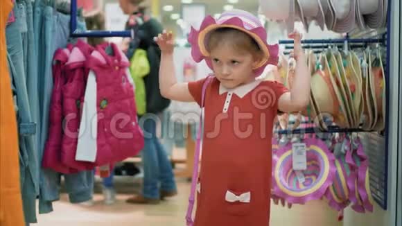 小女孩在商店里试穿帽子和包玩得开心笑得开心小孩购物视频的预览图