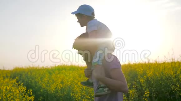 爸爸带着男孩在草地上玩耍快乐的童年爸爸和孩子在阳光下被愚弄成花朵视频的预览图