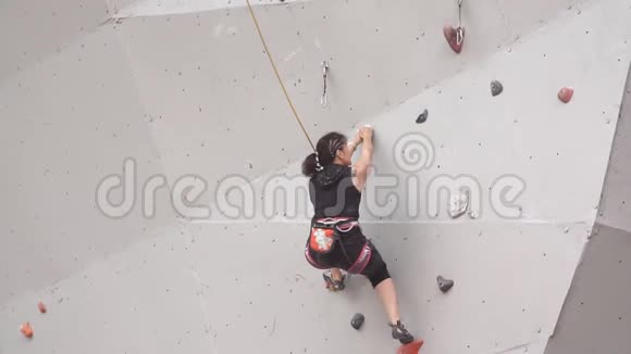 有登山设备的女登山运动员慢动作年轻的运动女孩爬上攀岩墙上的岩石视频的预览图