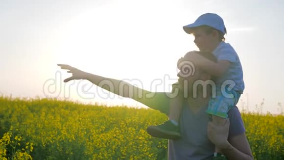 快乐的童年爸爸和儿子在阳光明媚的天气里散步爸爸和小男孩一起走过田野手牵着地平线视频的预览图