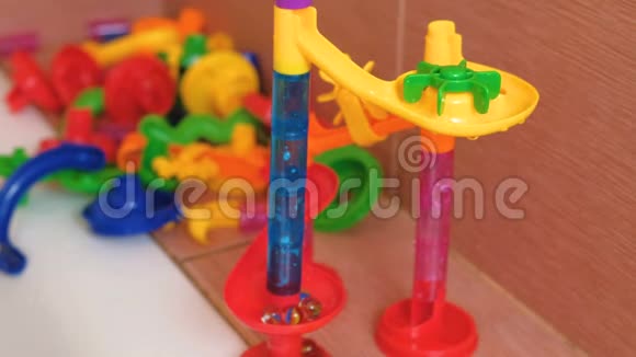 玻璃球从浴室里彩色设计师的塑料滑梯上滚动视频的预览图
