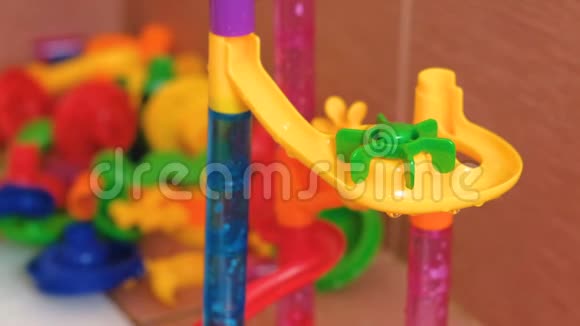 玻璃球从浴室里彩色设计师的塑料滑梯上滚动视频的预览图