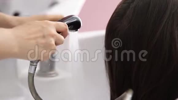 美丽的金发女人在美容院洗头发概念头按摩视频的预览图