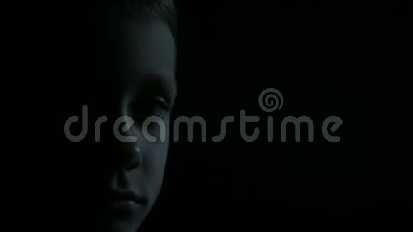 悲伤男孩特写半张脸在黑暗中视频的预览图