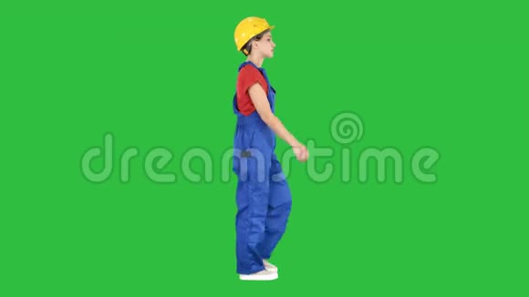 年轻的女建筑工人穿着黄色硬帽走在绿色屏幕上Chroma键视频的预览图