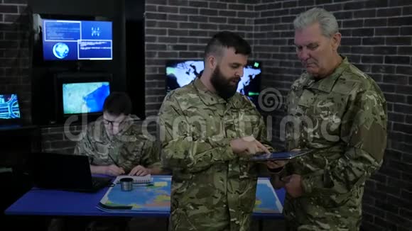 战争中心将军和军官在军事总部观看数字平板电脑视频的预览图