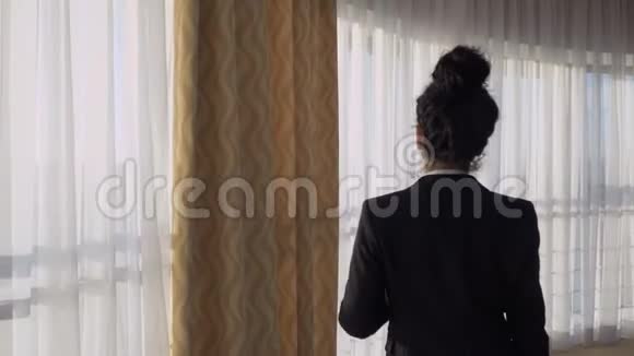 女商人在酒店房间的窗户附近散步视频的预览图
