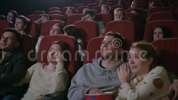 年轻人在电影院看电影电影院的浪漫约会视频的预览图