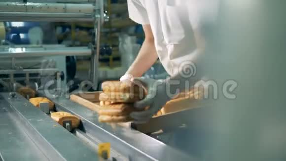 戴防护手套的工人把新鲜的烤卷放在传送带上视频的预览图