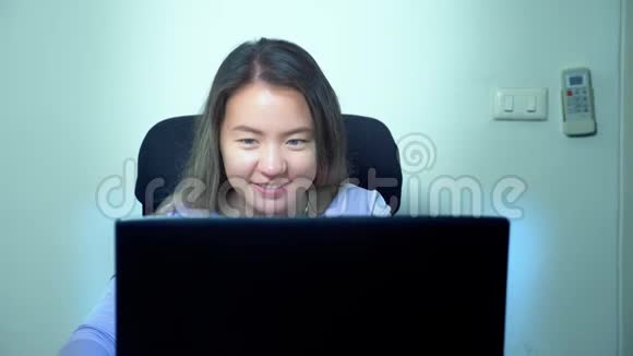 可爱的亚洲女孩在办公室的桌子上使用笔记本电脑视频的预览图