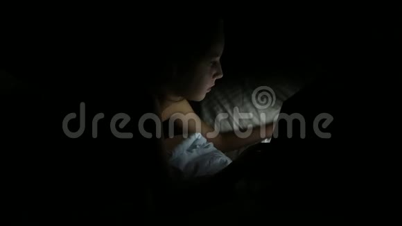 可爱的小女孩晚上躺在床上她拿着平板电脑年轻漂亮的女人用平板电脑躺在床上视频的预览图