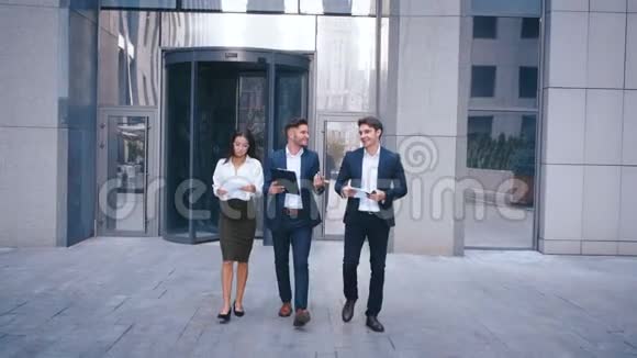 成功的商业人士在中央商务区讨论商业和步行两名青年男子和一名女子视频的预览图