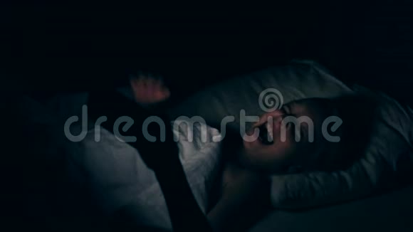 女孩在床上看智能手机上的视频时笑了女孩晚上躺在卧室的床上视频的预览图