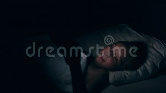 小女孩晚上躺在床上看着智能手机女孩在手机上看电影时哭了儿童视频的预览图