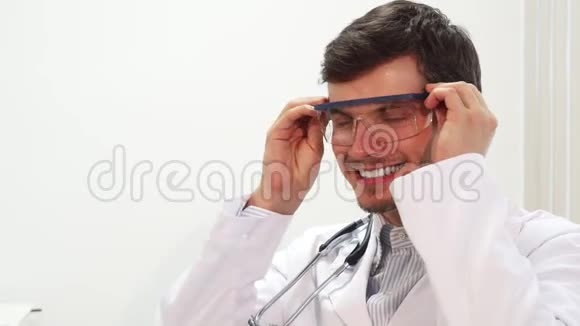 一位微笑的医生戴上特殊的透明实验室眼镜视频的预览图