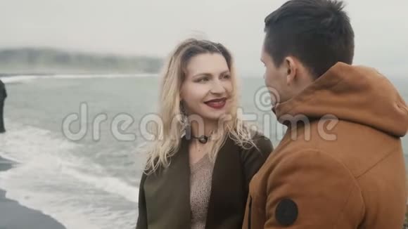 在冰岛巨魔脚趾岩附近的黑色海滩上年轻情侣的浪漫约会游客一起度过时光视频的预览图