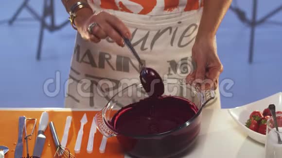 紫罗兰物质从勺子滴到宽边的大玻璃锅里视频的预览图