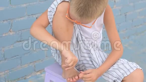 戴眼镜的少年用剪刀剪脚趾甲视频的预览图