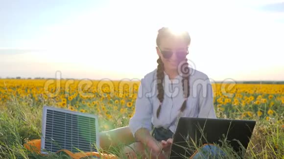 自然能源快乐的年轻女性在户外使用太阳能光伏电池板女性在带笔记本的背光中视频的预览图