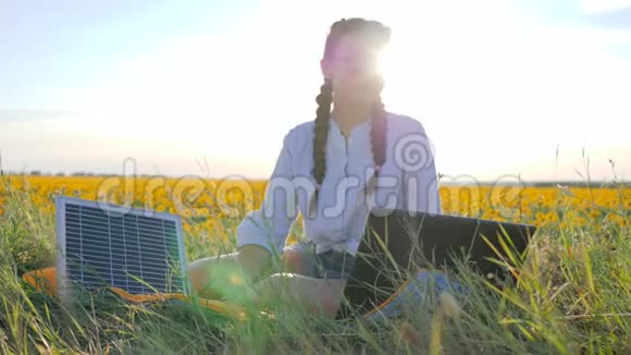 可再生能源女孩用太阳能电池在向日葵上的笔记本电脑上说话年轻女子用太阳能电池供电视频的预览图