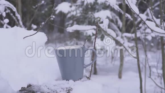 冬天下雪的时候男人用手在森林里放一杯热饮料视频的预览图