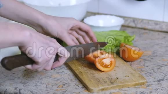 特写镜头中的女人用手把西红柿切成小块放在餐桌上的砧板上慢动作视频的预览图