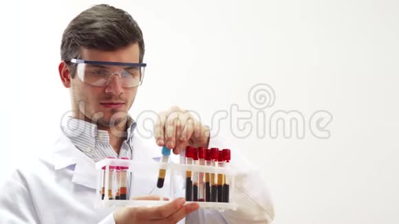 医生戴着特殊的实验室眼镜检查带血的试管视频的预览图