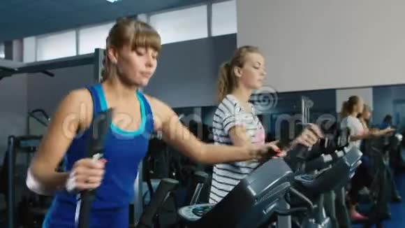 两位有魅力的女性在健身房接受椭圆教练训练视频的预览图