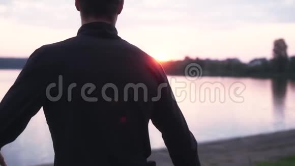 慢动作男子伸展双腿靠近安静的湖后景男运动员准备在美丽的乡村跑步视频的预览图