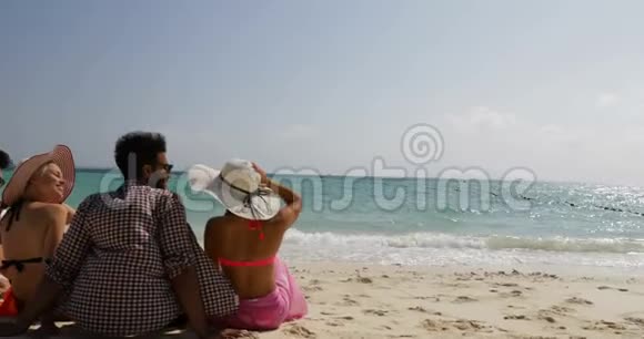人们坐在沙滩上聊天开心地举起双手后仰男男女女在夏季交流游客群视频的预览图