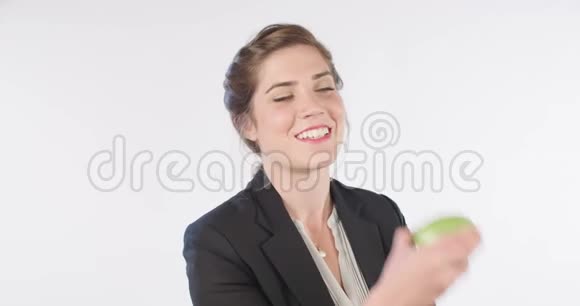 一个女人在白色的工作室里吃一个大绿苹果视频的预览图