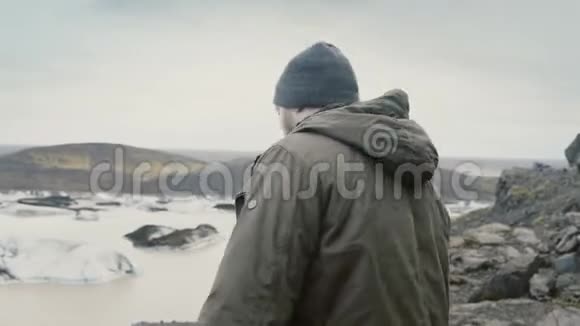 年轻的帅哥在瓦特纳霍卡尔冰湖附近的山上徒步旅行看着冰岛的冰川视频的预览图