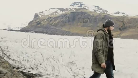 年轻英俊的男人独自走在岸上游客探索冰岛的瓦特纳霍卡尔冰湖视频的预览图