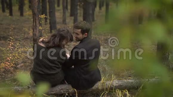 林中秋初年轻夫妇花时间在树林里他们坐在树桩上谈笑风生视频的预览图