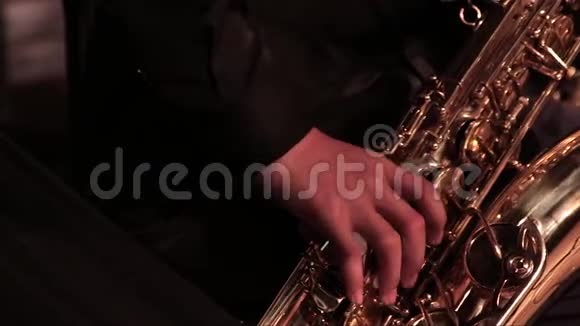 一个男人在爵士乐队的金色萨克斯管上穿着黑色西装特写镜头视频的预览图