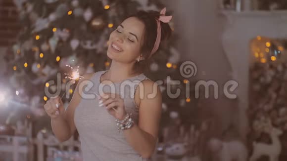 一个年轻的女孩坐在靠近新年树的房间里房间里有圣诞装饰和灯光视频的预览图
