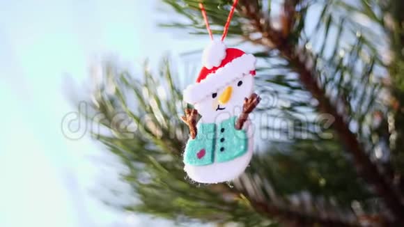 特写圣诞玩具挂在白雪覆盖的圣诞树树枝上冬天霜冻下雪晴天视频的预览图